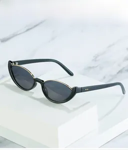 Détail de lunettes de soleil œil de chat noires avec bordure en métal doré sur la monture