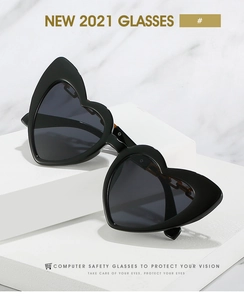Detail of heart-shaped sunglasses with thick black frames and dark translucent lenses