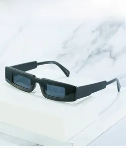Détail de lunettes de soleil rectangulaires noires étroites sur un bloc blanc