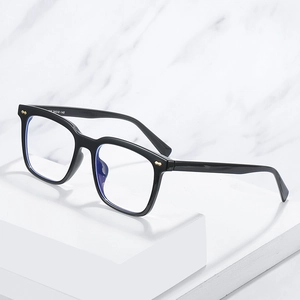 Modern black TR90 full-rim eyeglasses with golden bow rivets on marble background