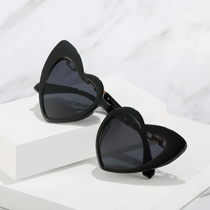 Fashion heart shaped sunglasses with black frame and gold chain temple detail on white stand