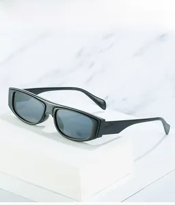 Detail of glossy black square frame sunglasses with dark gray lenses on a white pedestal