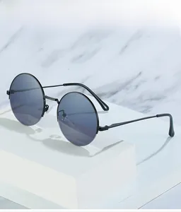 Detail of round vintage metal sunglasses with blue lenses on a white marble surface