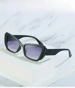 Detail of black cat-eye sunglasses with purple gradient lenses on marble stand