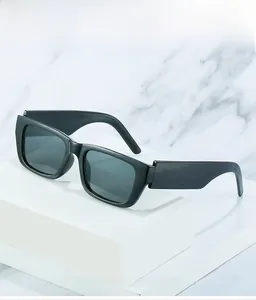 Detail view of thick-framed square sunglasses with wide temples on marble background