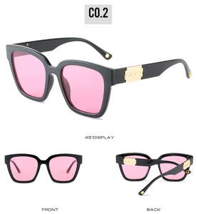 Detail view of square black sunglasses with pink lenses and gold wave metal accents