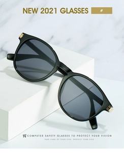 Détail de lunettes noires avec charnières en métal doré sur un support minimaliste