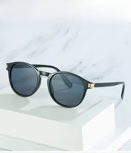 Gros plan de lunettes de soleil rondes vintage noires avec charnières dorées sur marbre