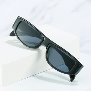 Minimalist thick rectangle sunglasses with matte black frames and dark lenses on a pedestal