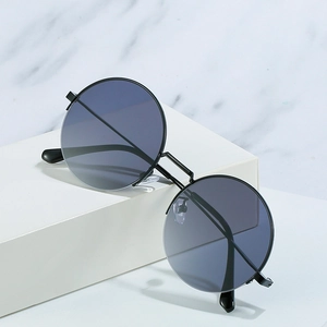 Retro round metal sunglasses with dark gray lenses and double bridge design on marble background