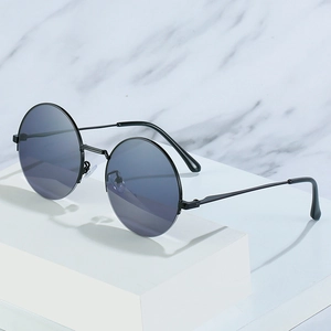 Retro round metal sunglasses with dark gray lenses on a minimalist marble background