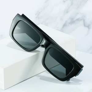 Modern thick-frame square sunglasses with dark grey lenses on a marble background