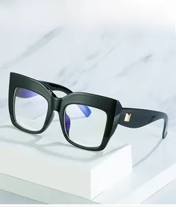 Detail of black cat-eye glasses frame featuring a golden D-shaped metal logo on the temple