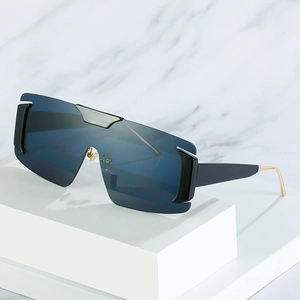 Fashionable oversized one-piece sunglasses with blue lenses and gold metal temples on a pedestal