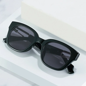 Classic black square frame sunglasses with dark lenses displayed on a white stand