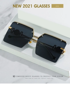 Detail of oversized square rimless sunglasses with grey lenses and gold metal bridge