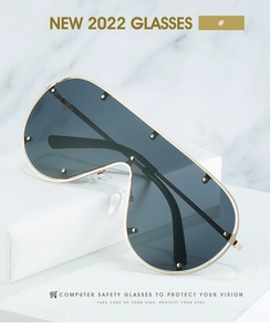 Détail de lunettes de soleil à monture dorée avec rivets argentés et verres gris foncé