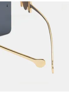 Detailed close-up of slim gold metal temples and dark square lenses on fashion sunglasses