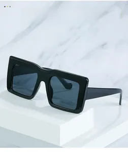 Détail de lunettes de soleil punk à monture carrée noire sur socle géométrique