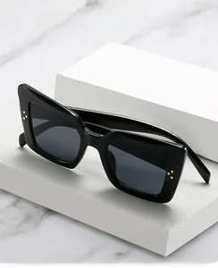 Detail of square black sunglasses with thick frames and iconic gold triple dot rivets