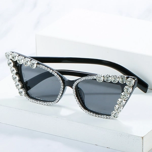 Chic cat eye sunglasses with rhinestones and dark grey lenses on marble background