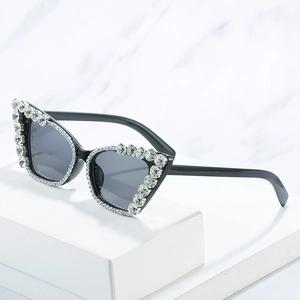 Cat eye sunglasses with oversized white rhinestones and dark lenses on a marble surface