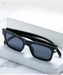 Détail de lunettes de soleil rectangulaires noires avec rivets en métal sur marbre blanc