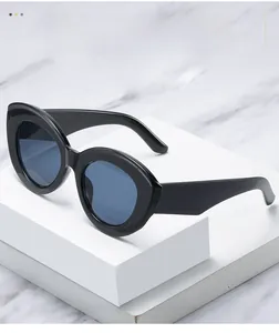 Macro shot of black cat-eye sunglasses with blue lenses on white marble background