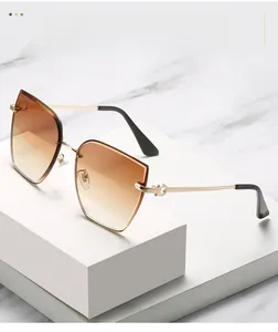 Detailed macro view of gold metal temples and gradient brown lenses on rimless sunglasses