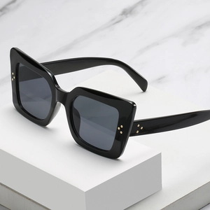 Classic black oversized cat-eye sunglasses with three golden metal rivets on chunky frame