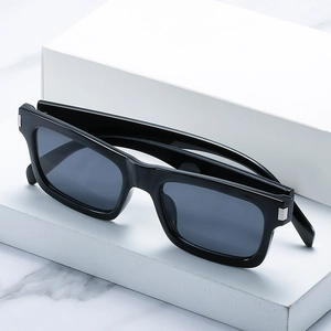 Lunettes de soleil carrées noires avec détails métalliques argentés sur un support