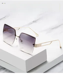 Detail einer übergroßen quadratischen Sonnenbrille mit hohlen Goldmetallbügeln und Verlauf