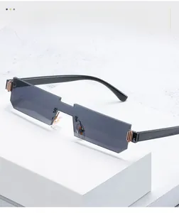 Detail of rimless rectangle sunglasses with grey lenses and gold metal accents