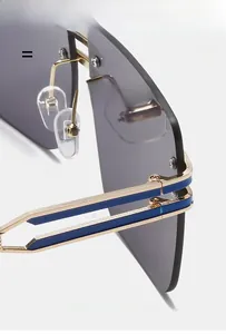 Detail view of gold metal hinges and dark grey lenses on oversized rimless sunglasses