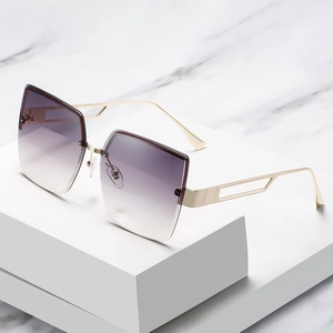 Übergroße randlose Sonnenbrille mit lila Farbverlauf und goldenen Metallbügeln auf Marmor