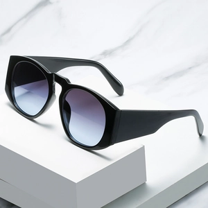 Oversized black round sunglasses with gradient lenses on a white minimalist pedestal