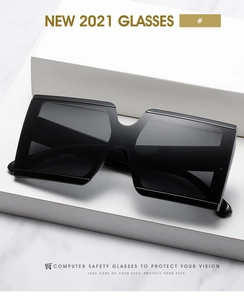 Close-up of black oversized square sunglasses on marble background with gold accents