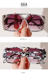 Detailed view of oversized tortoiseshell sunglasses with crystal embellishments and purple lenses