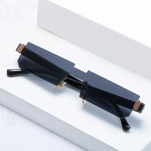 Frameless geometric sunglasses with black lenses and gold metal hinges on white stone