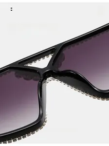 Close-up of oversized square sunglasses with purple gradient lenses and rhinestone trim