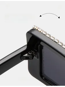 Detailed close-up of the durable metal hinge and rhinestone trim on black oversized sunglasses