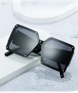Detailed side view of oversized square sunglasses with black frame and golden rivets