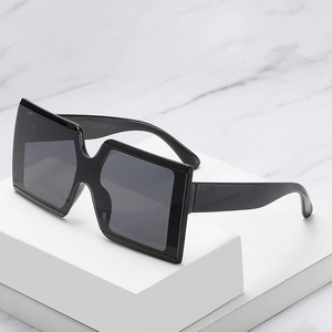 Chic oversized square sunglasses with black frames and dark grey lenses on marble background