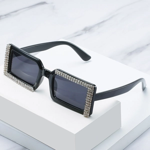 Chic black rectangular sunglasses with sparkling rhinestone borders on marble surface