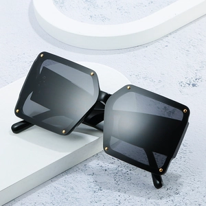 Square oversized sunglasses in black frame with gold rivet accents and dark gray lenses
