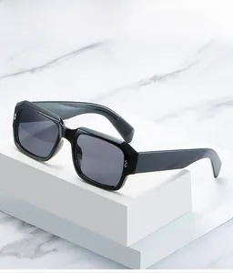 Detail of black rectangular sunglasses with silver accents on a geometric marble stand