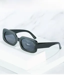 Close-up of black retro wide-frame sunglasses on a white geometric minimalist stand