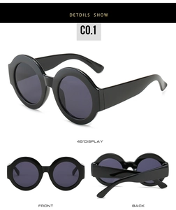 Detail view of large round dual-tone sunglasses in black with wide temples and dark lenses