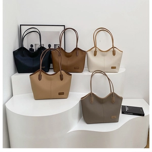 Detailed view of five faux leather tote bags in various colors on a white tiered stand