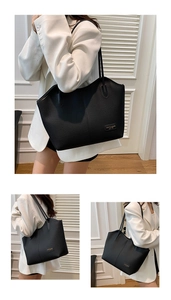 Detail of the black pebbled leather tote bag with gold metal logo and sleek stitching